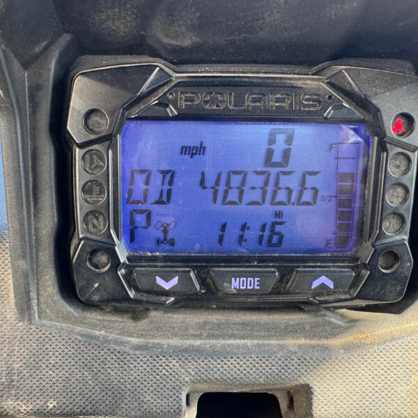 Close-up of a Polaris digital instrument cluster showing 0 mph, time 11:15, and mode buttons nearby (MODE).