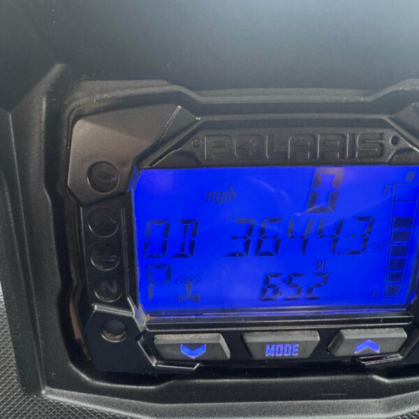 Close-up of a Polaris motorcycle digital gauge in a black housing, with a blue display showing mph and the word MODE on a button beneath.