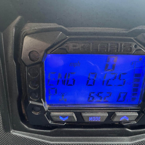 Blue backlit car instrument cluster with digital speed readout and status icons framed by a rugged dashboard housing
