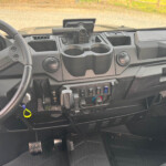 Interior view of a pickup truck dashboard with cup holders, gear shifter, and control panel on the center console
