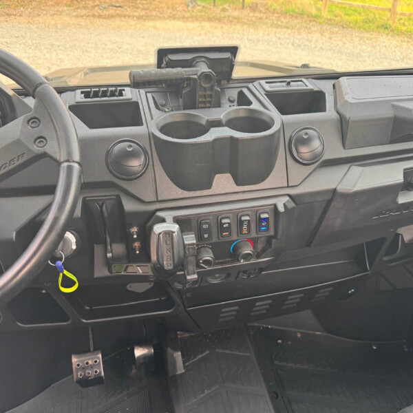 Interior view of a pickup truck dashboard with cup holders, gear shifter, and control panel on the center console