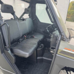 Interior of a Polaris off-road vehicle: front passenger and driver seats, rugged dashboard, and entry step visible.