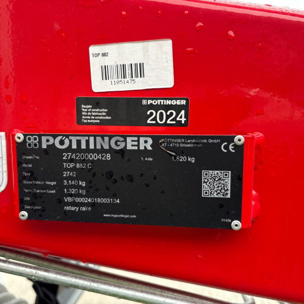 Close-up of a red Pöttinger agricultural implement with a 2024 model label and a barcode sticker.