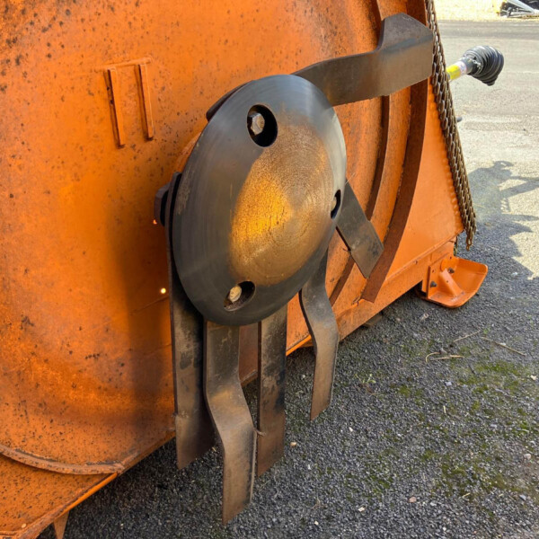 Close-up of a rusted orange industrial machine showing a large circular gray plate and metal brackets