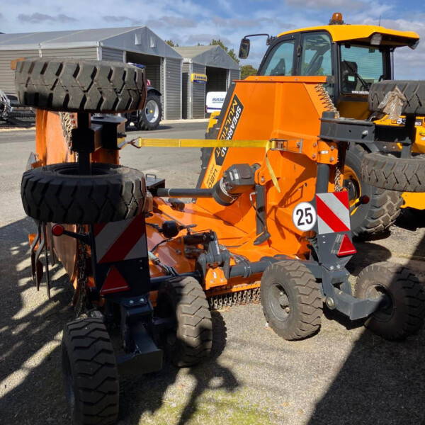 Orange heavy machinery with large tires in an outdoor equipment yard, with grey tents in the background.
