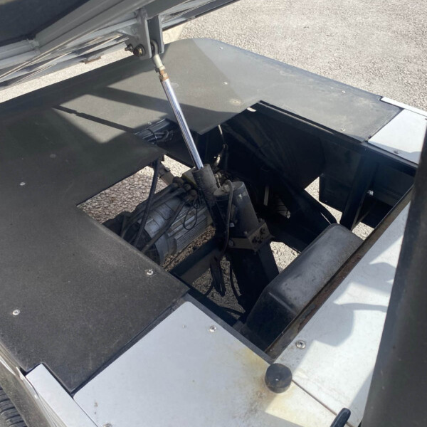 Close-up of a hydraulic strut holding open a metal dump truck tailgate