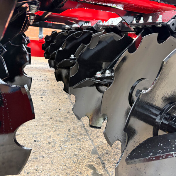 Close-up of jagged black steel shredding blades with bolts and red frame, part of heavy machinery used for material size reduction