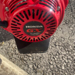 Close-up of a red Honda GX270 small engine cover with vent slots and logo visible.