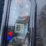Vehicle instrument cluster with orange needles, frost on the glass, and visible fuel gauge and speedometer.