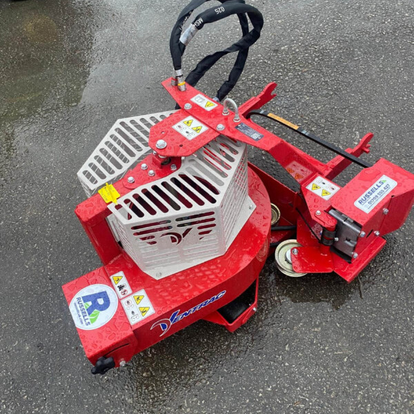 Red industrial machine with metal basket and black wrapped hoses on wet asphalt surface.