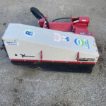 Red stump grinder attachment on a trailer resting on rough pavement; branding includes DENTRAC and KC220 model label on the side.