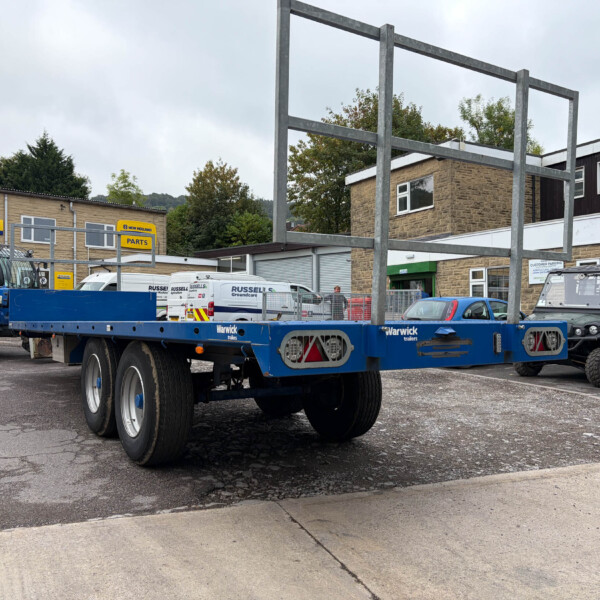 Industrial equipment yard with a blue trailer and construction machinery beside a brick building.